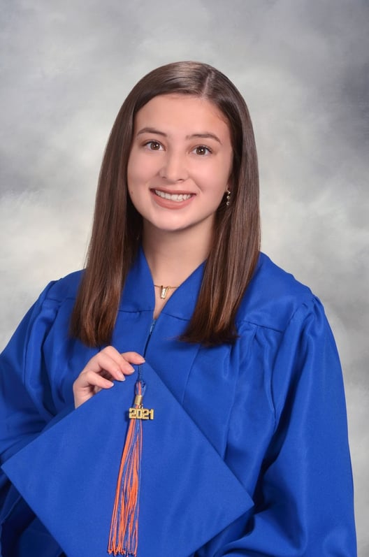Rachel Bartley wearing the SJND blue cap and gown in a graduation photo.