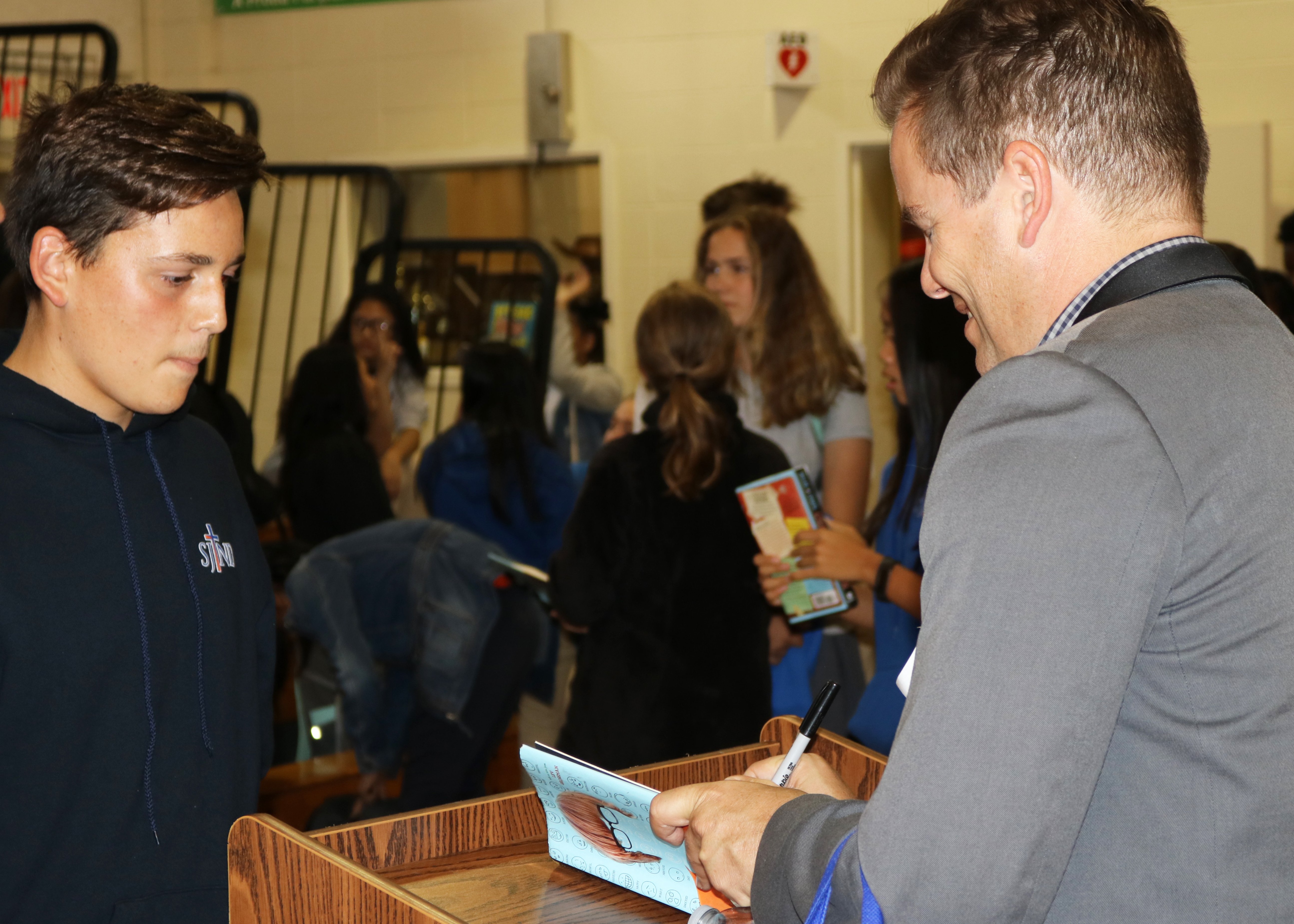 Stentz signs SJND students’ copies of his novel, ‘Colin Fisher.’