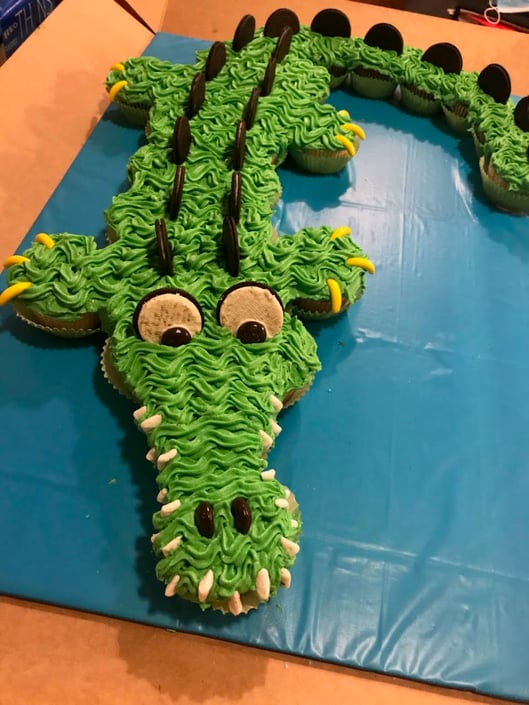A green alligator cupcake cake made with Oreos, vanilla cupcakes, and green icing.